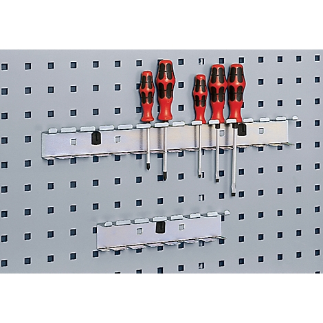Screwdrivers in a metallic holder on a perforated tool wall.