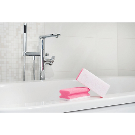 Deux éponges roses et blanches reposent sur le bord d'une baignoire blanche. À l'arrière-plan, un robinet chromé.