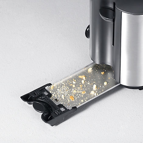 Detailaufnahme eines Toasters, bei dem die Krümelschublade teilweise herausgezogen ist und Krümel zeigt.