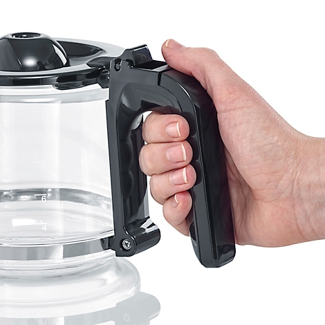 Eine Hand hält den schwarzen Griff eines Kaffeekannen-Glaskorpus. 