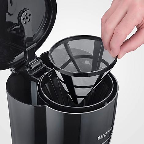 Nahaufnahme einer schwarzen Kaffeemaschine mit eingesetztem Filter. Eine Hand hält den Filter.