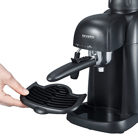 Close-up van een zwarte Severin espressomachine. Een hand houdt de lekbak vast.