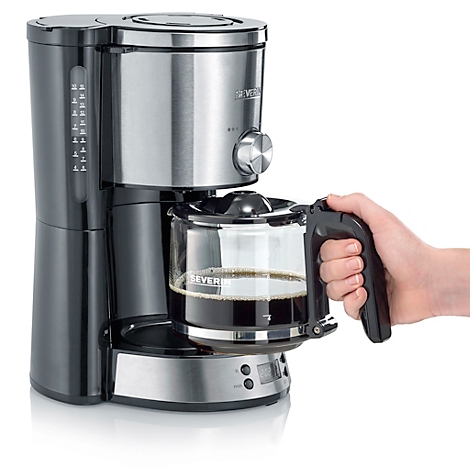 Kaffeemaschine mit Glaskanne, gefüllt mit Kaffee, gehalten von einer Hand.