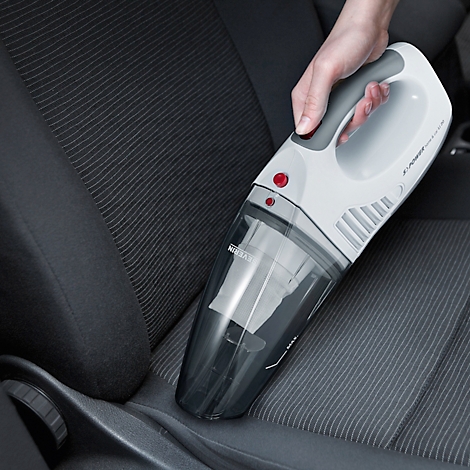 Handheld vacuum cleaner used to clean a car seat. The vacuum is white and grey with a red button.