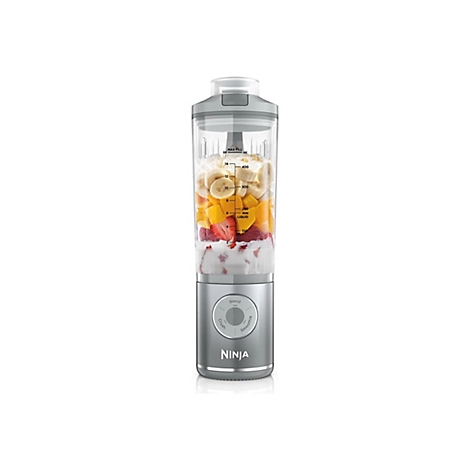 Ninja Standmixer mit gefülltem Behälter aus Bananen, Mangos, Erdbeeren und Joghurt vor weißem Hintergrund.