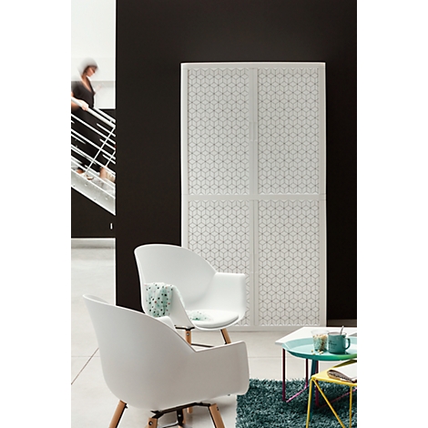 White room divider with geometric pattern, two white chairs, a small table, a person on a staircase.