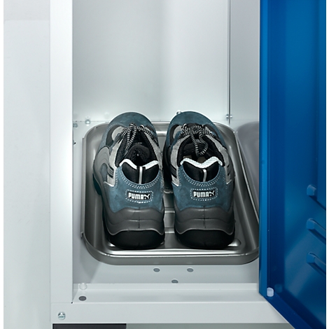 Two blue Puma shoes stand in a metal shoe compartment in a white cabinet. Blue, grey, and black make up the dominant colors.