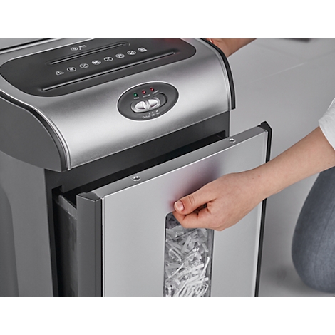 Person opening paper shredder container. Shredded paper strips are visible through the window.