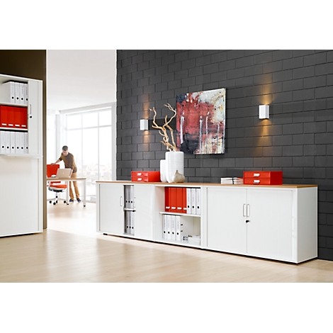 Office with white cabinets, red files, a person, and art on a gray wall. Mood: modern.