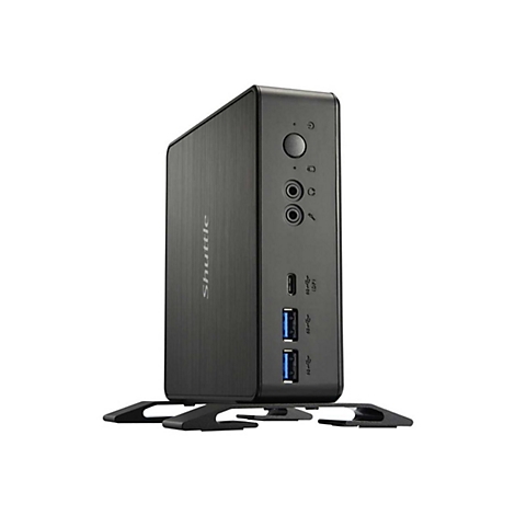 Mini PC noir avec le logo Shuttle. L'avant montre les ports et un bouton. Le PC repose sur un support.