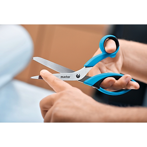 Person hält eine blaue Schere. Die Schere ist geöffnet und die Klinge zeigt nach oben. Der Name "martor" ist auf der Schere zu sehen.