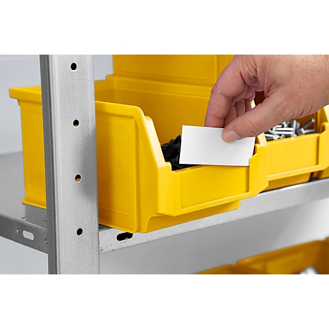 Hand steckt leeres weisses Etikett in eine gelbe Sichtlagerbox in einem Metallregal.