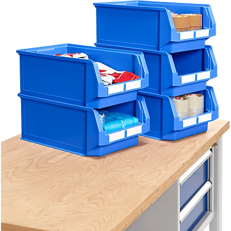 Blaue Kunststoffboxen auf einer Holzoberfläche mit Inhalten wie Kleidung, Geschenkpapier und Klebeband.