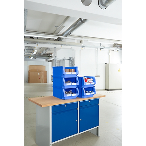 Blaue Werkzeugkästen stehen auf einer Werkbank in einem Lager. Hinter dem Werkzeug eine leere Halle.