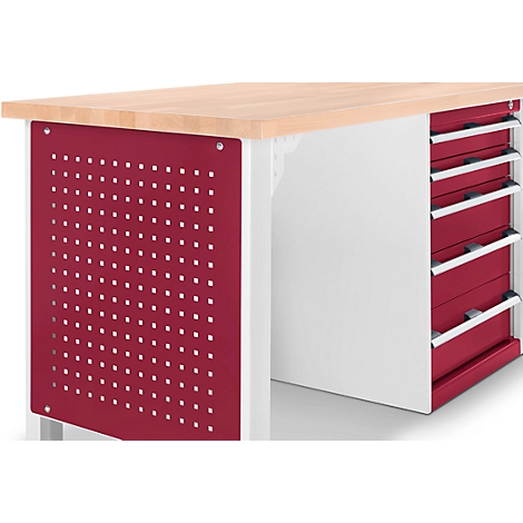 Close-up of a workbench. Wooden top, red perforated side and drawers. White frame and silver handles.