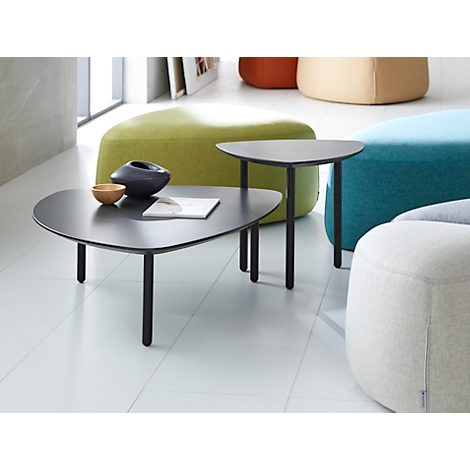 Two black triangular side tables with a book, a bowl, and a vase. Colorful cushions in the background.