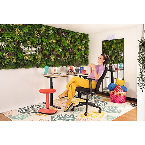 Femme se détend dans un fauteuil de bureau, tasse de café, mur vert, pantalon jaune, ambiance relax.