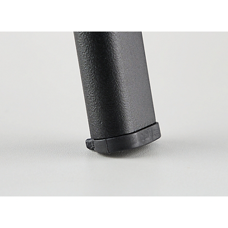 Gros plan de la partie inférieure d'un chargeur noir à texture striée reposant sur une surface blanche.