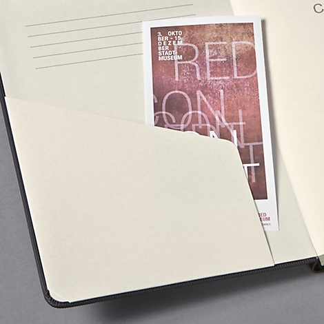 Un cahier ouvert avec une carte dans la poche intérieure. La carte indique "RED ON ART".