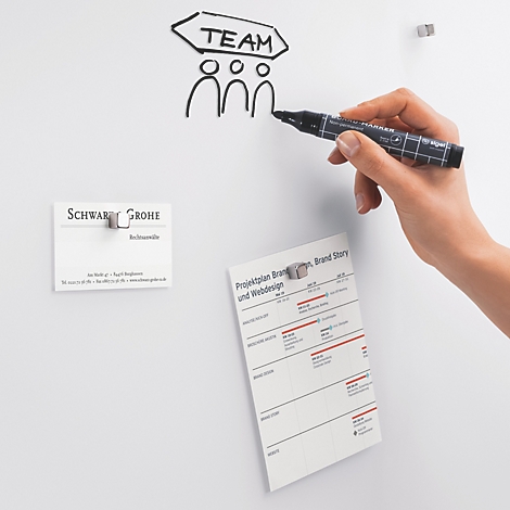 Hand tekent "Team" op whiteboard; visitekaartje en notitievel bevestigd.