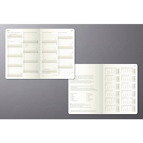 Double page de carnet beige clair avec calendriers et texte sur fond gris. La page ouverte affiche des aperçus annuels et des listes.