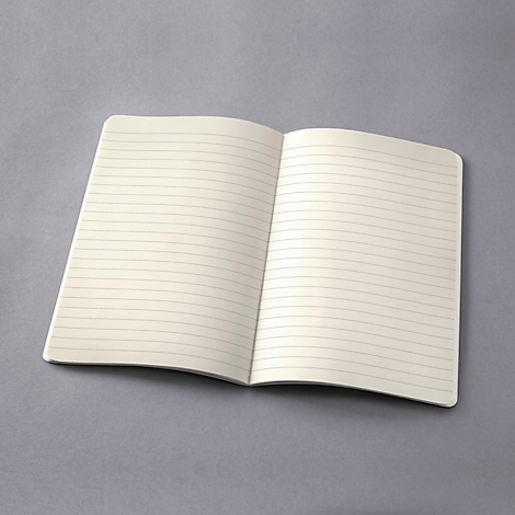 Un carnet ouvert avec des lignes sur une surface grise. Les pages crème sont vierges.