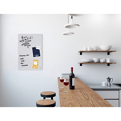 Eine Küche mit hellen Wänden, Holztisch und Weinflaschen. Ein Whiteboard hängt an der Wand mit Notizen und Magneten.