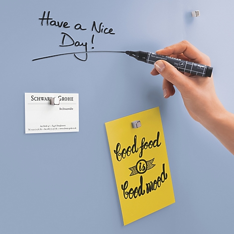 Hand schreibt mit schwarzem Stift auf einer blauen Wand: „Have a nice day!“; darunter Notizen.