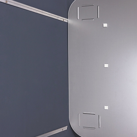 Graue Wand mit Metallplatte. Die Platte hat quadratische Aussparungen und kleine quadratische Elemente.