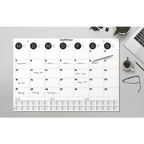 Ein Tischkalender mit dem Monat September. Darauf notierte Termine. Zudem ein Stift, Laptop, Brille und Kaffee.