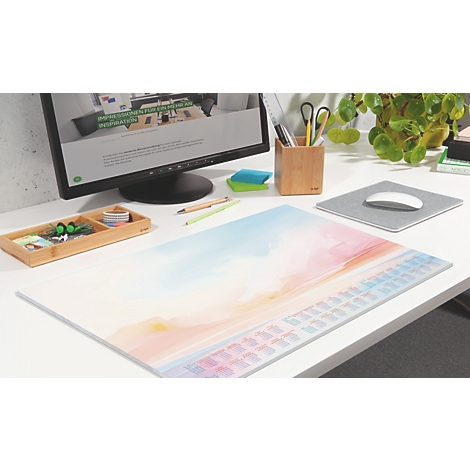 Schreibtisch mit Mauspad in Pastellfarben. Auf dem Pad eine Tastatur, daneben Monitor und Pflanzen.