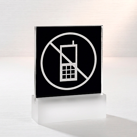 Quadratisches Schild auf weissem Sockel mit durchgestrichenem Handy-Symbol als Verbotshinweis.