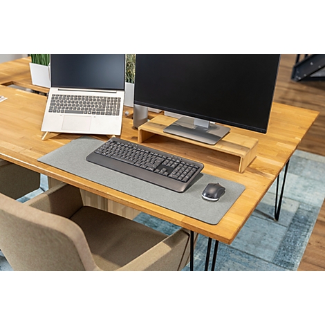 Schreibtisch mit Laptop, Monitor, Tastatur und Maus. Holzplatte, grauer Teppich. Bürostuhl im Vordergrund.