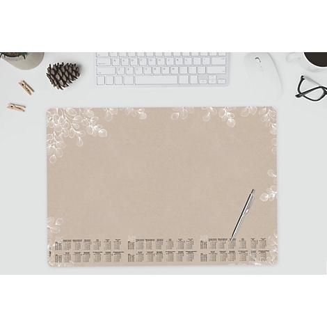 Beige bureau-onderlegger met wit bladerpatroon en kalender. Pen ligt ernaast.