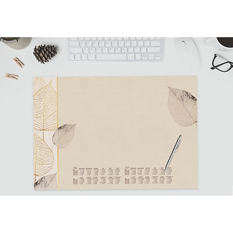 Tapis de bureau beige avec des feuilles et un calendrier, stylo à côté. Clavier, souris, lunettes en arrière-plan.