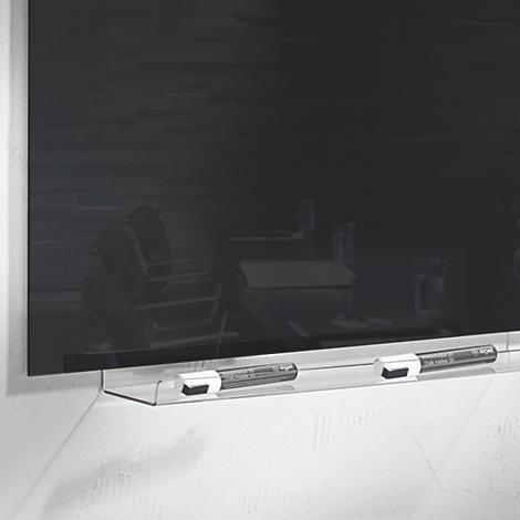 Eine schwarze Glas-Magnettafel mit zwei Stiften. Im Hintergrund sind schemenhaft Stühle und Tische zu erkennen.