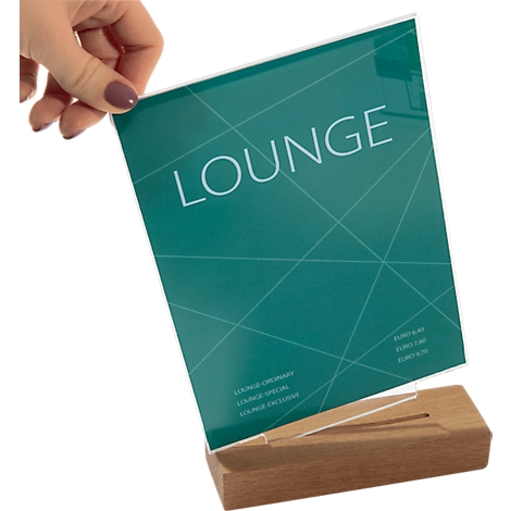 A hand holds a green sign with the word "LOUNGE". The sign stands on a wooden base.