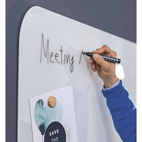 Une personne écrit "Meeting" sur un tableau blanc avec un stylo noir. Une image est fixée au tableau avec des aimants.