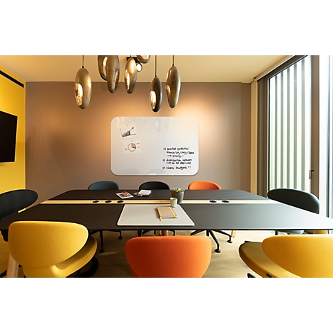 Salle de conférence avec table, chaises et tableau blanc. Les couleurs vives dominent, mobilier moderne.