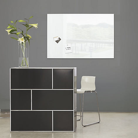 Armoire noire avec cadre blanc, chaise et tableau avec notes. Dans un vase: fleurs blanches.