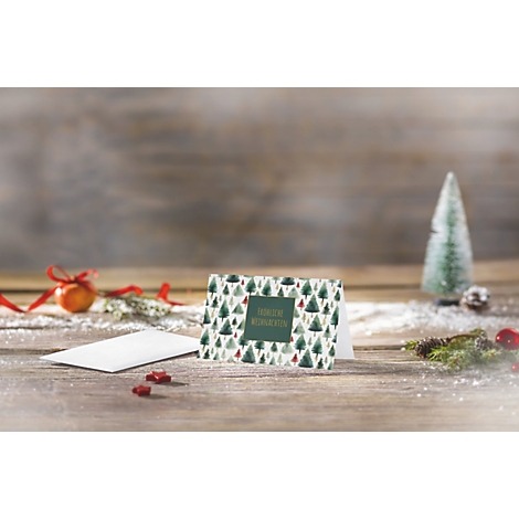 Weihnachtskarte mit Tannenbaum-Muster auf einem rustikalen Holztisch mit Dekoration.