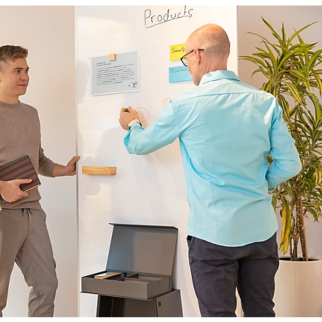 Zwei Männer in einem Büro stehen vor einem Whiteboard, auf dem Konzepte mit Post-its und Zeichnungen visualisiert sind.