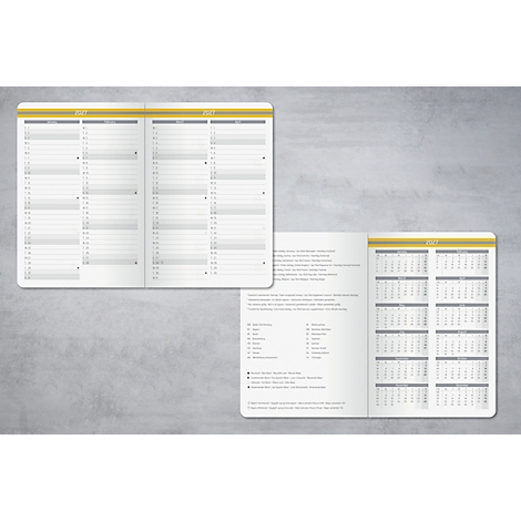 Geöffnete Notizbücher, das Jahreskalender und Textseiten zeigt. Auf grauem Hintergrund.