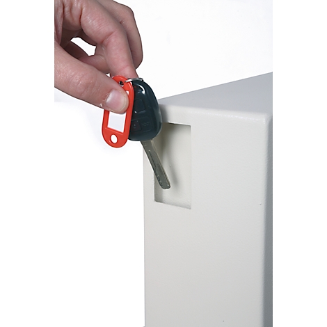 Een hand houdt een autosleutel voor een witte doos met een sleutelgat.
