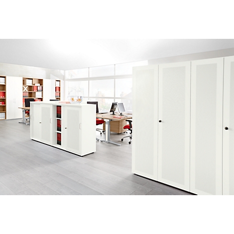 Bright office with cabinets, desks and chairs. Large windows illuminate the room. Files in the cabinets.