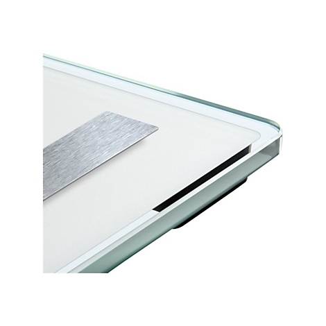 Detailansicht einer Personenwaage aus Glas mit abgerundeter Ecke und einem gebürsteten Metallelement.