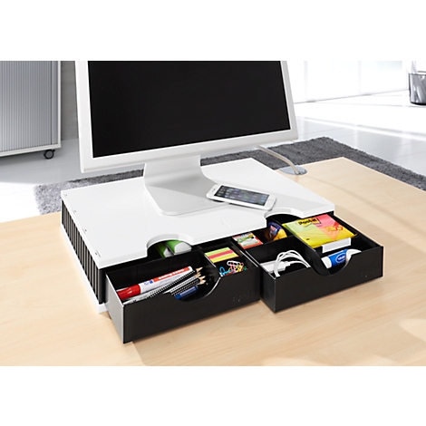 Desk with monitor, drawers for office supplies. The drawers contain pens, sticky notes, a cell phone and other items.