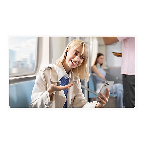 Junge Frau im Zug telefoniert per Smartphone, sie trÃ¤gt einen Trenchcoat und OhrhÃ¶rer.