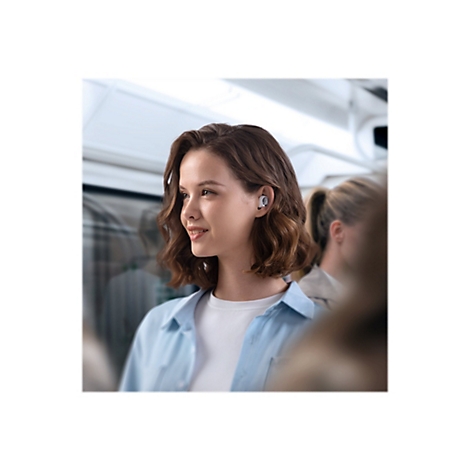 Junge Frau mit Ohrhörern in der U-Bahn, lächelt.