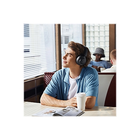 Ein Mann in einem Restaurant, der KopfhÃ¶rer trÃ¤gt und aus dem Fenster schaut.